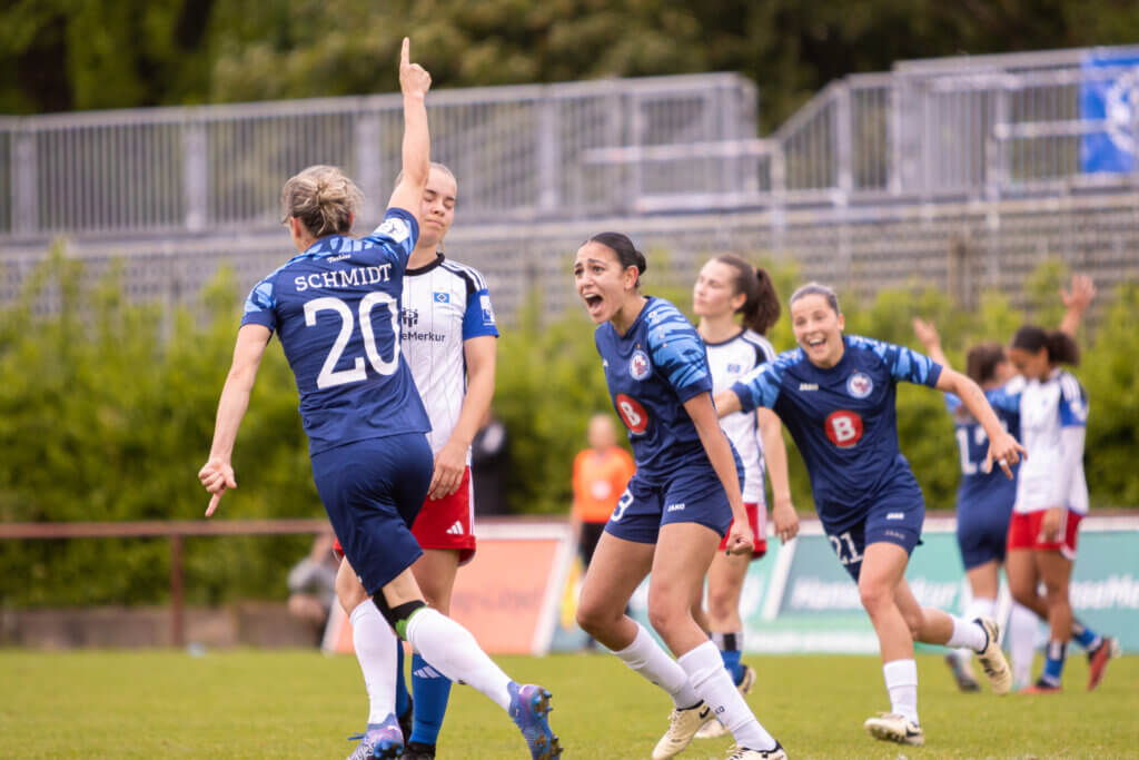 Zu sehen sind Bianca Schmidt, welche nach ihrem geschossenen Tor den Arm in die Luft streckt, als auch Maria Almasri und Noa Selimhodzic, die sich ebenfalls mit Bianca Schmidt freuen. 