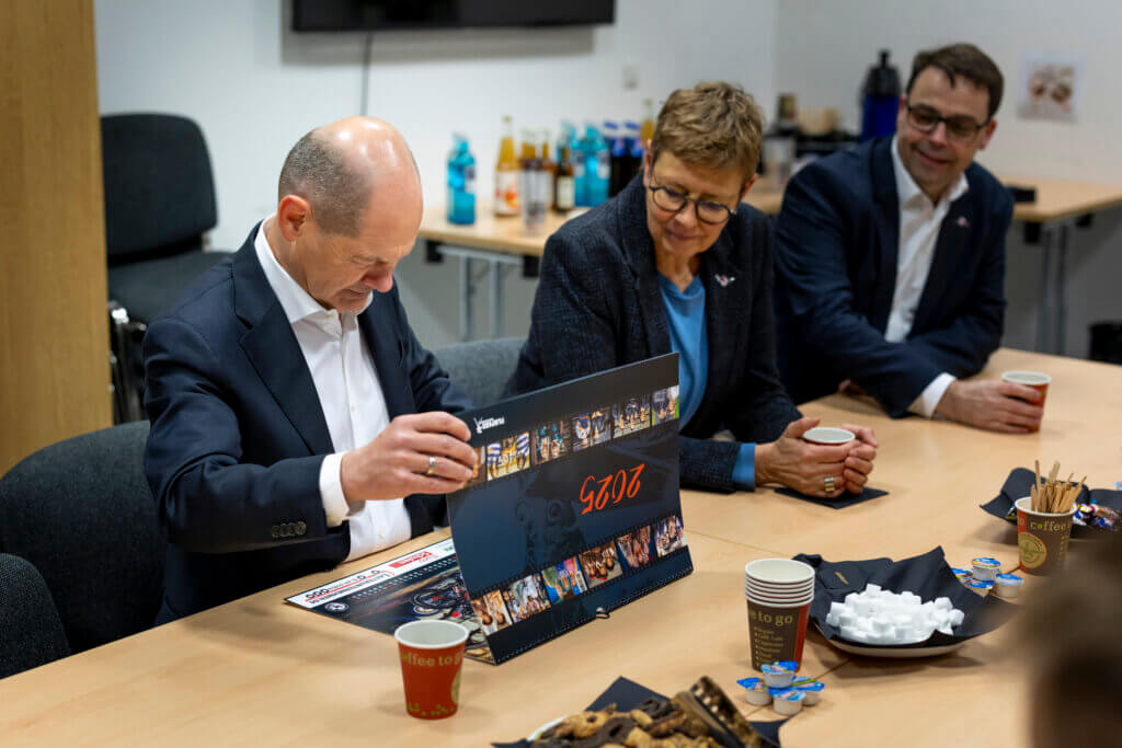 Olaf Scholz inspiziert den Kalender für das Jahr 2025 von Turbine Potsdam. 